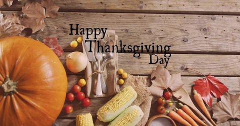 Rustic thanksgiving harvest table with pumpkin, corn, cherry tomatoes and autumn leaves