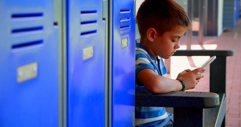 Young Boy by School Lockers Concentrating on Smartphone - Download Free Stock Images Pikwizard.com