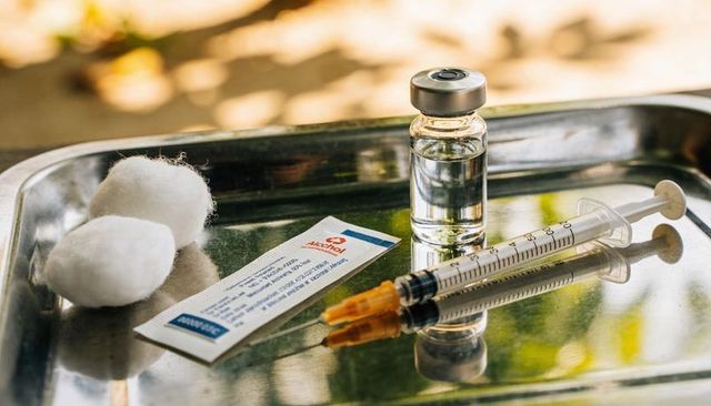 Vaccination preparation on stainless tray with syringe vial cotton swab in warm sunlight
