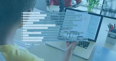 Man pointing at laptop displaying translucent bar chart overlay in collaborative office