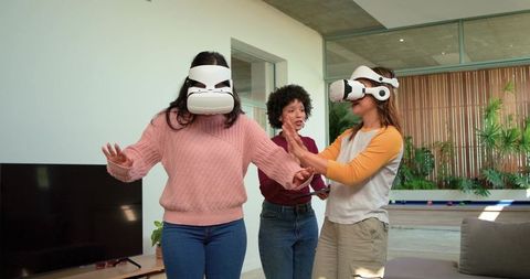 Diverse friends exploring immersive vr game in modern lounge wearing white headsets