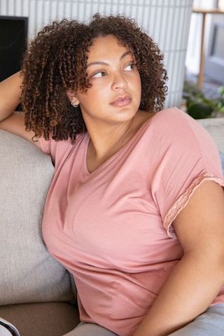 Relaxed African American Woman Contemplating on Gray Couch in Cozy Living Room