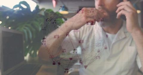 Mature professional talking on mobile, holding phone and resting hand by laptop with network overlay