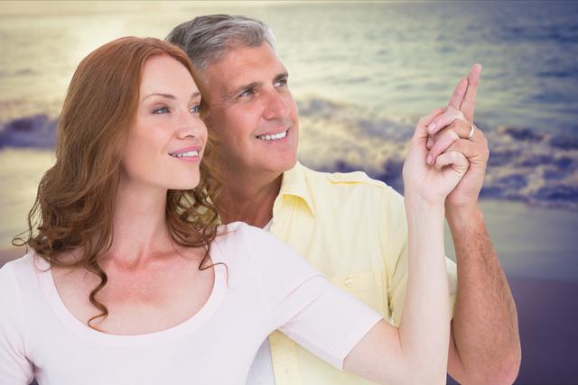 Digital composite of Loving couple pointing away at beach