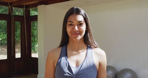 Smiling Asian Female Yoga Instructor in Sunny Room