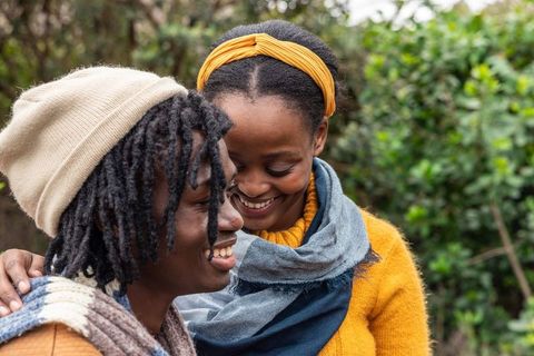 African american couple smiling and embracing outdoors in cozy knitwear and scarves