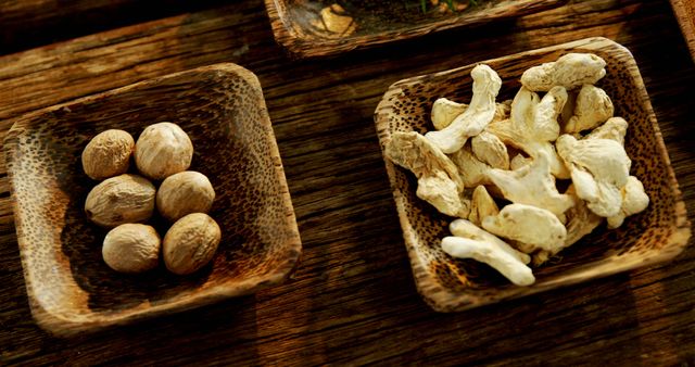 Two wooden bowls on a rustic table contain unshelled and shelled nuts, showcasing a natural and healthy snack option. The contrast between the smooth nuts and the textured wood emphasizes the organic and wholesome quality of the food.