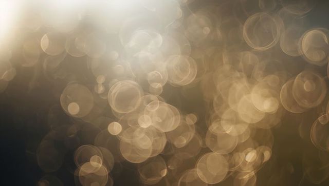 Golden amber bokeh lights creating warm abstract background with soft circular glints