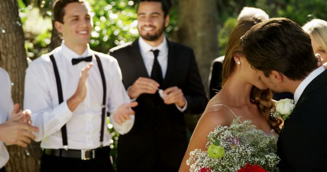 Bride and groom kissing surrounded by friends at outdoor wedding - Download Free Stock Images Pikwizard.com