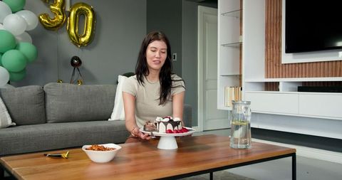 Woman Celebrating Birthday Holding Cake on Coffee Table