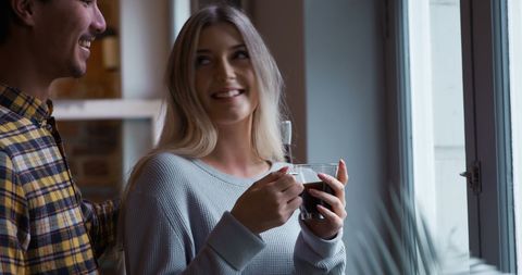 Happy Couple Sharing Coffee Relaxing by Window at Home