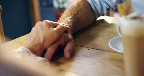 Elderly Couple Holding Hands in a Cozy Cafe Moment