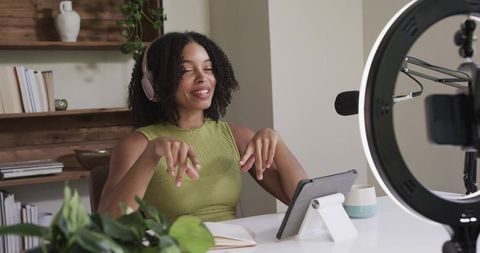 African american creator recording podcast in home office with ring light, microphone, tablet