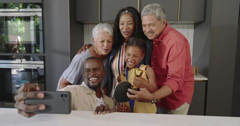 Multigenerational family taking smartphone selfie celebrating young table tennis champion
