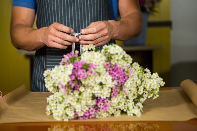 Mid section of male florist preparing a flower bouquet in flower shop