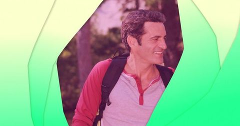 Smiling man wearing backpack framed by green papercraft cutouts in outdoor forest portrait