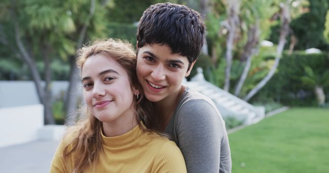Happy caucasian lesbian couple embracing and smiling in front of house. Togetherness, relationship and love, domestic life,unaltered.