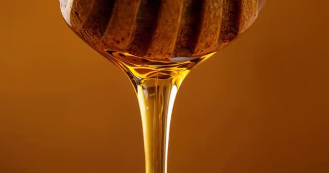 Slow-Motion Drizzling Honey Stream from Wooden Dipper