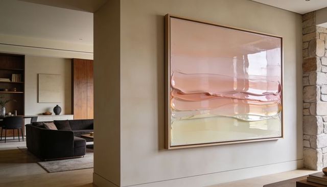 Glossy abstract wall art in minimal open living space with warm pastel layers