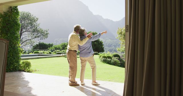 Rear view of caucasian senior couple pointing towards a directing standing near the garden. retirement senior couple lifestyle living concept