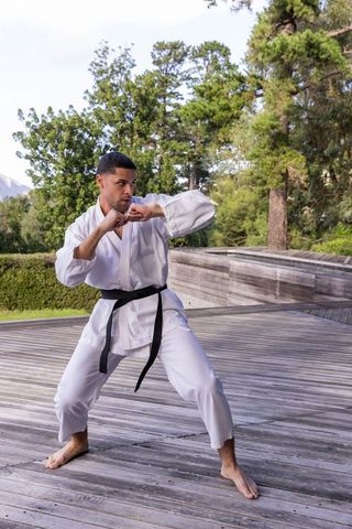 Focused martial artist practicing karate outdoors on wooden platform
