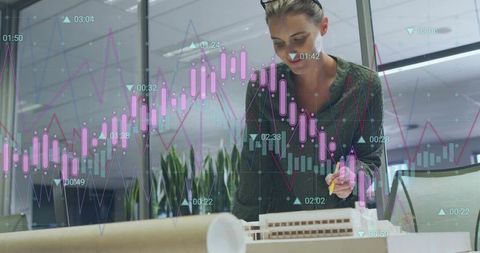 Architect analyzing model holding pen with candlestick financial charts overlay in studio