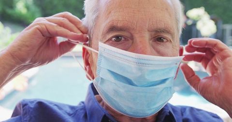 Senior Man Adjusting Face Mask Outdoors