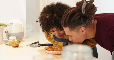 Couple leaning over and smelling freshly baked pie on bright modern kitchen countertop