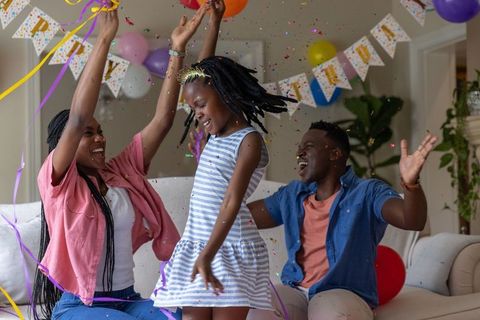 African american family celebrating birthday with confetti, balloons and joyful child
