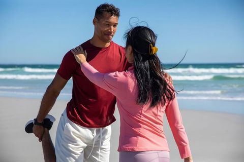 Couple Practicing Quadriceps Stretch on Sunny Beach