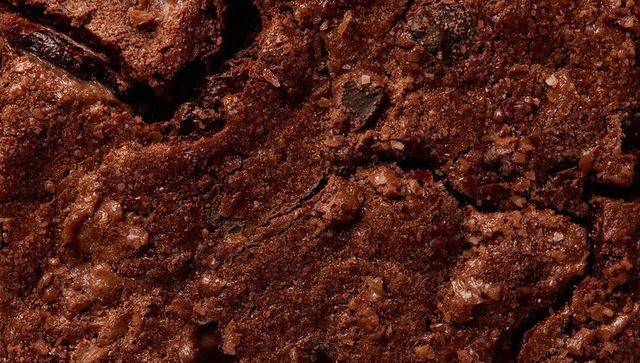 Macro close-up of fudgy chocolate brownie with cracked glossy crust and sea salt