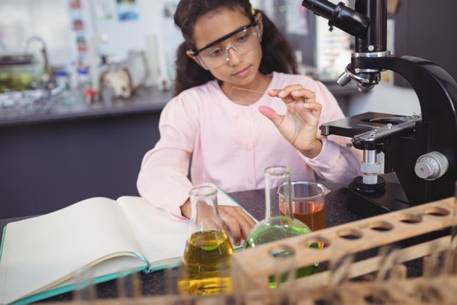 Concentrated elementary student examining sample by desk at science laboratory