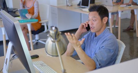 Young Businessman Engaged in Phone Call in Busy Office