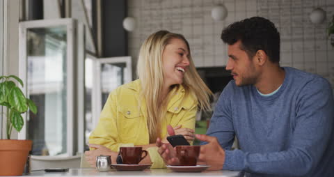 Happy Couple in Café Using Smartphone, Drinking Coffee Together