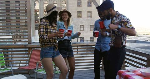Young Friends Celebrating at Rooftop Party with Drinks and Dancing