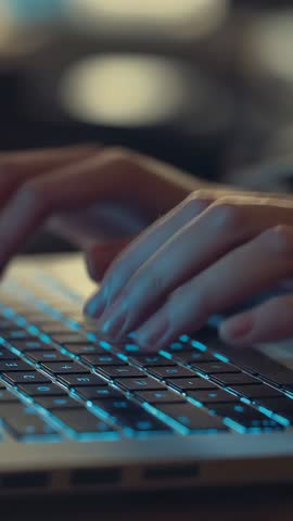 Vertical video showing hands typing on backlit laptop keyboard for focused productivity