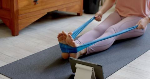 Woman Exercising with Resistance Band During Remote Workout