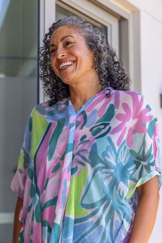 Smiling senior woman of african heritage wearing pastel floral blouse near sunlit doorway