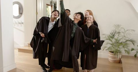 Multicultural Graduates Celebrating in Residential Entryway Taking Selfie in Black Gowns