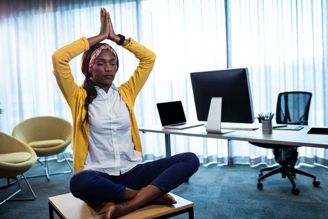 Businesswoman practicing yoga in an office environment, demonstrating work-life balance and stress relief techniques. Ideal for articles or blogs on mental wellness, workplace health, corporate well-being programs, or promoting a healthy office culture.