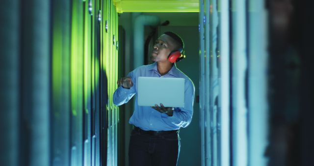 IT professional conducting maintenance in a data center, surrounded by server racks. Ideal for illustrating technology infrastructure, data management, network security, and IT industry concepts. Useful for articles, presentations, and advertising in technology, cyber security, and professional development domains.