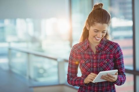 Smiling Woman Using Tablet in Modern Office with Natural Light