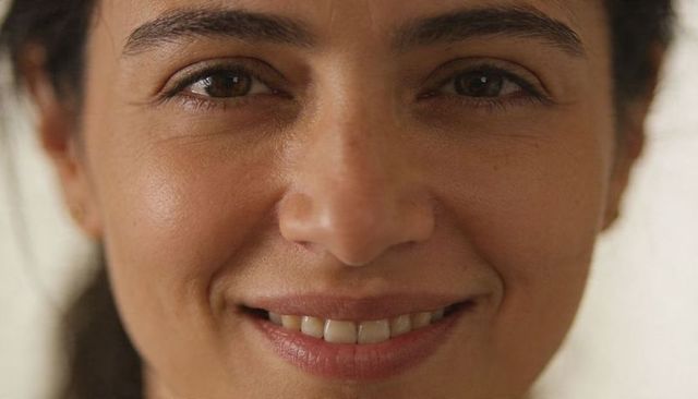 Close-up natural woman portrait smiling with visible skin texture and warm gentle gaze