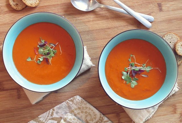 Two bowls of homemade tomato soup garnished with fresh microgreens. Ideal for uses related to recipes, food blogs, culinary websites, healthy eating promotions, or cooking tutorials. Perfect for illustrating cozy home-cooked meals or restaurant-quality presentations.
