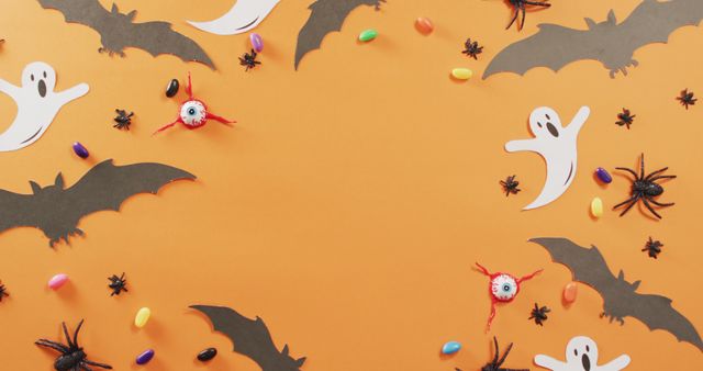 Close up of multiple halloween candies and toys against orange background. halloween festivity and celebration concept