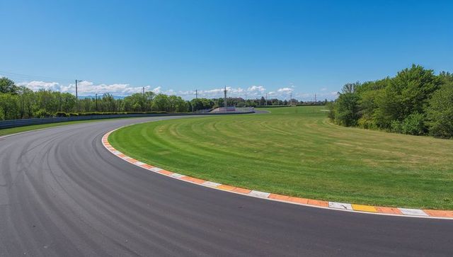 Sweeping left-hand curve on clear asphalt racetrack under blue sky