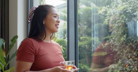 Contemplative woman enjoying rainy day indoors with tea