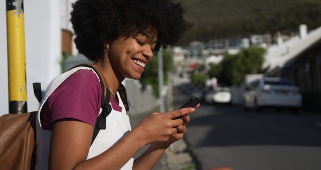 Smiling woman using smartphone sitting outside on sunny urban street - Download Free Stock Images Pikwizard.com