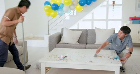 Men collaborating on living room party decor with balloons