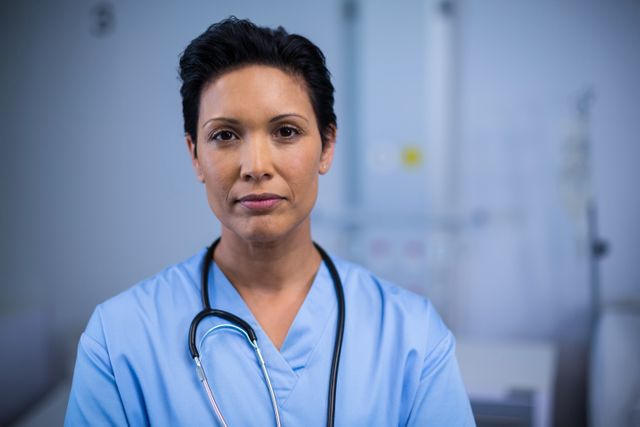Female nurse standing confidently in a hospital ward, wearing a stethoscope and medical uniform. Ideal for use in healthcare-related articles, medical websites, hospital brochures, and educational materials about nursing and healthcare professions.